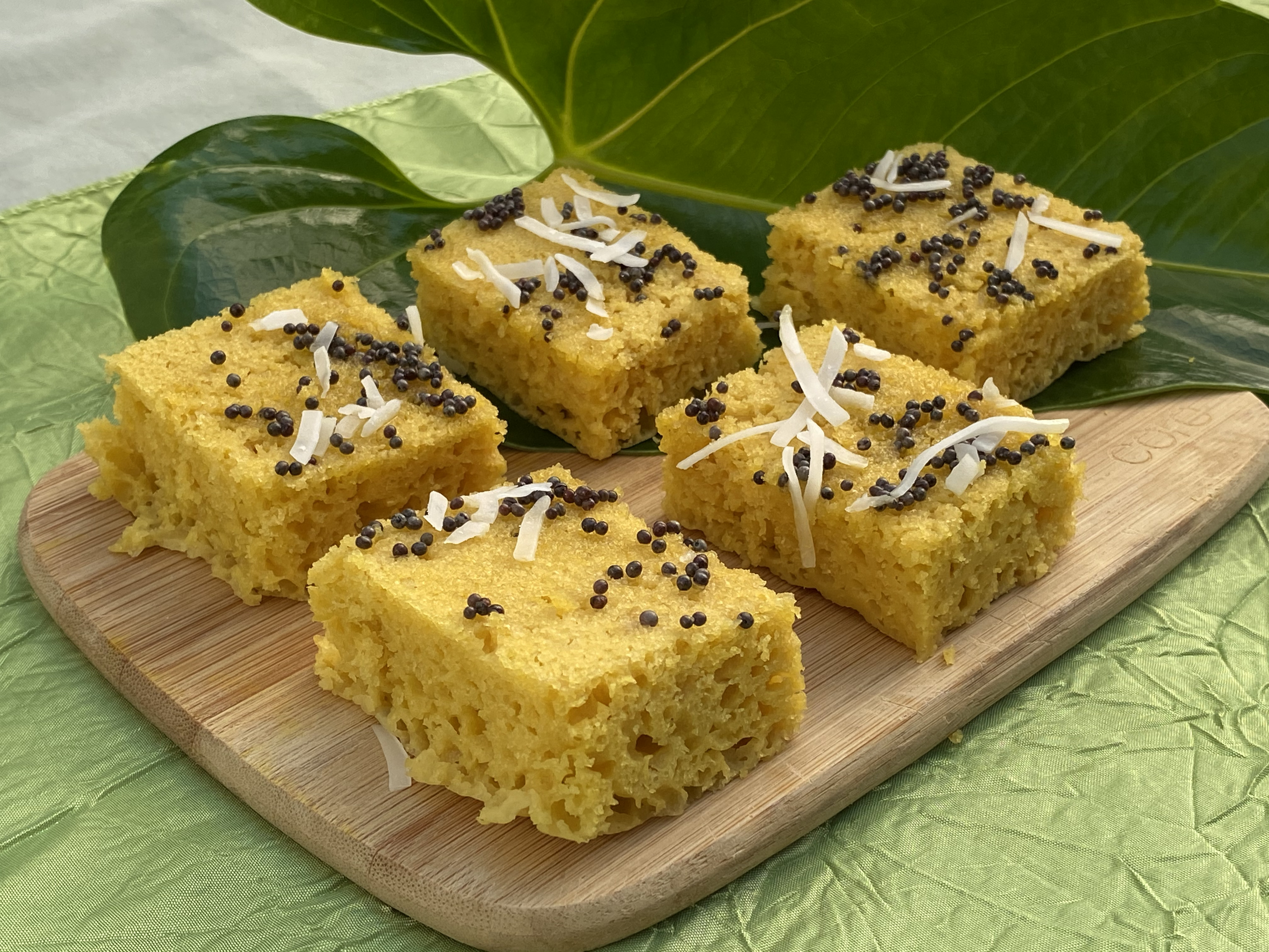 Dhokla served on a cutting board. Leaf as decorative element.